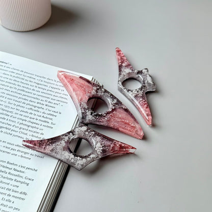 Handmade resin page holders in pink-gray color palette arranged next to an open book.